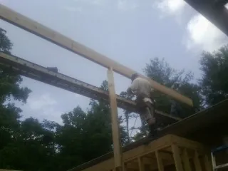 Carpenter setting a ridge beam over a new addition frame — Ice Dam Removal by Roofing Brothers in Guymon