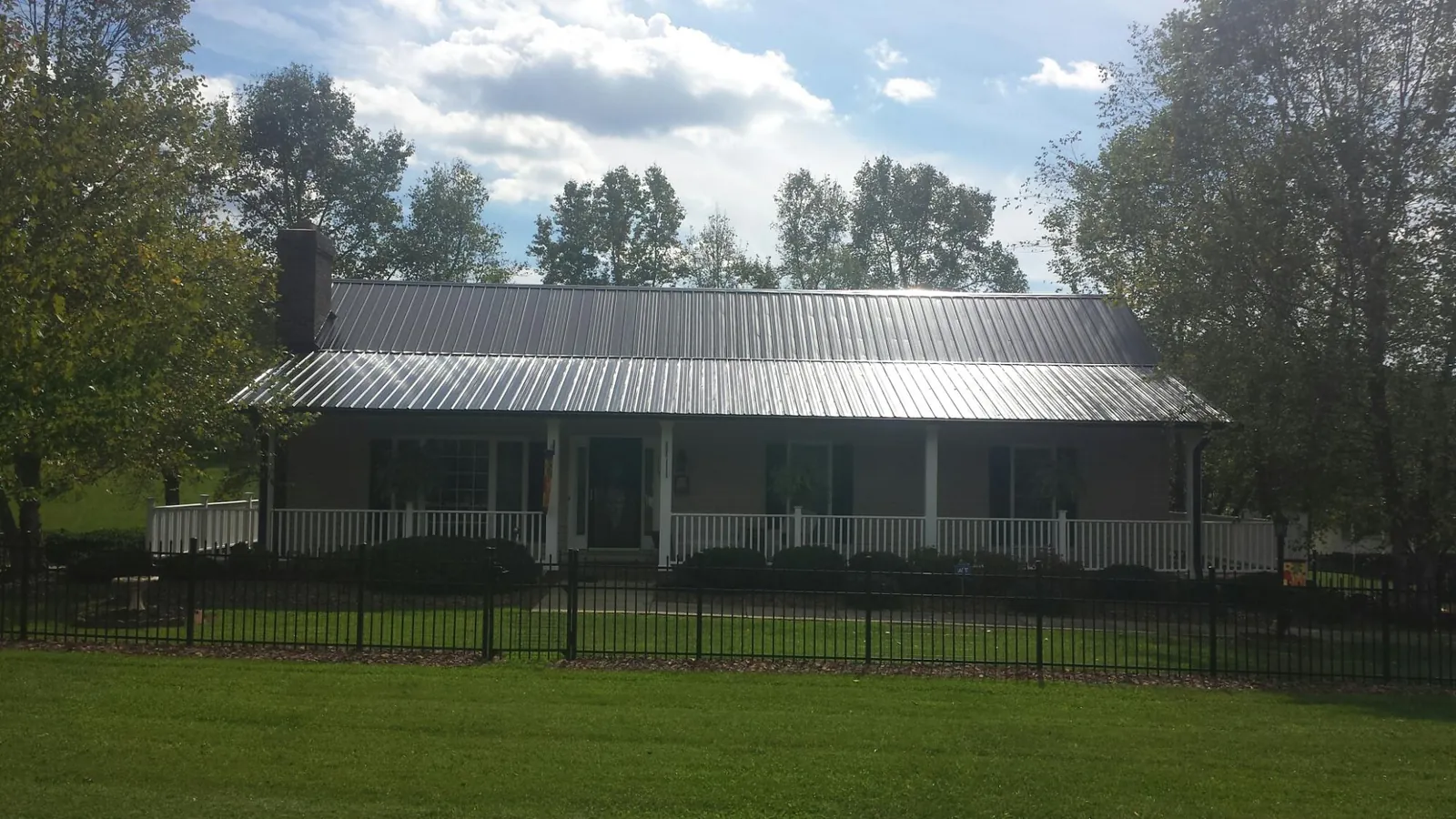 Gray metal roof on a brick ranch with a full width front porch — Gutter Guard Installation work by our crew in Guymon