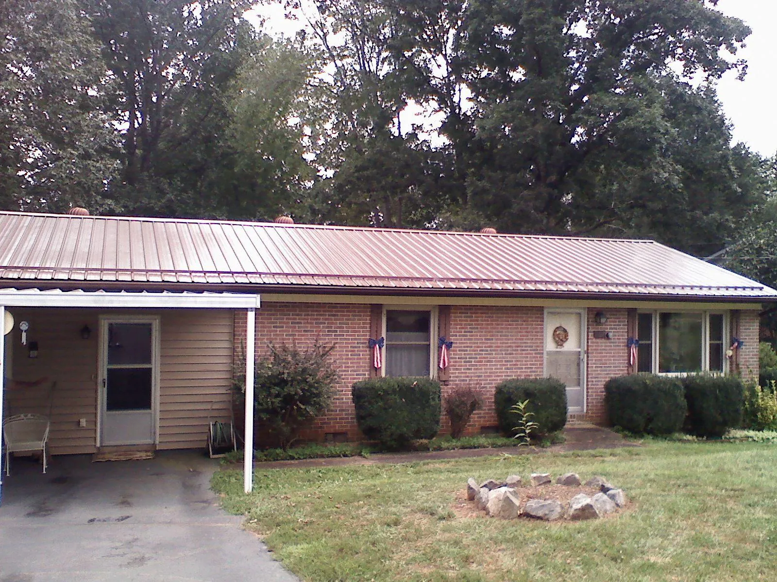 Bronze metal roof and carport on a brick ranch home — Roof Repair work by our crew in Guymon