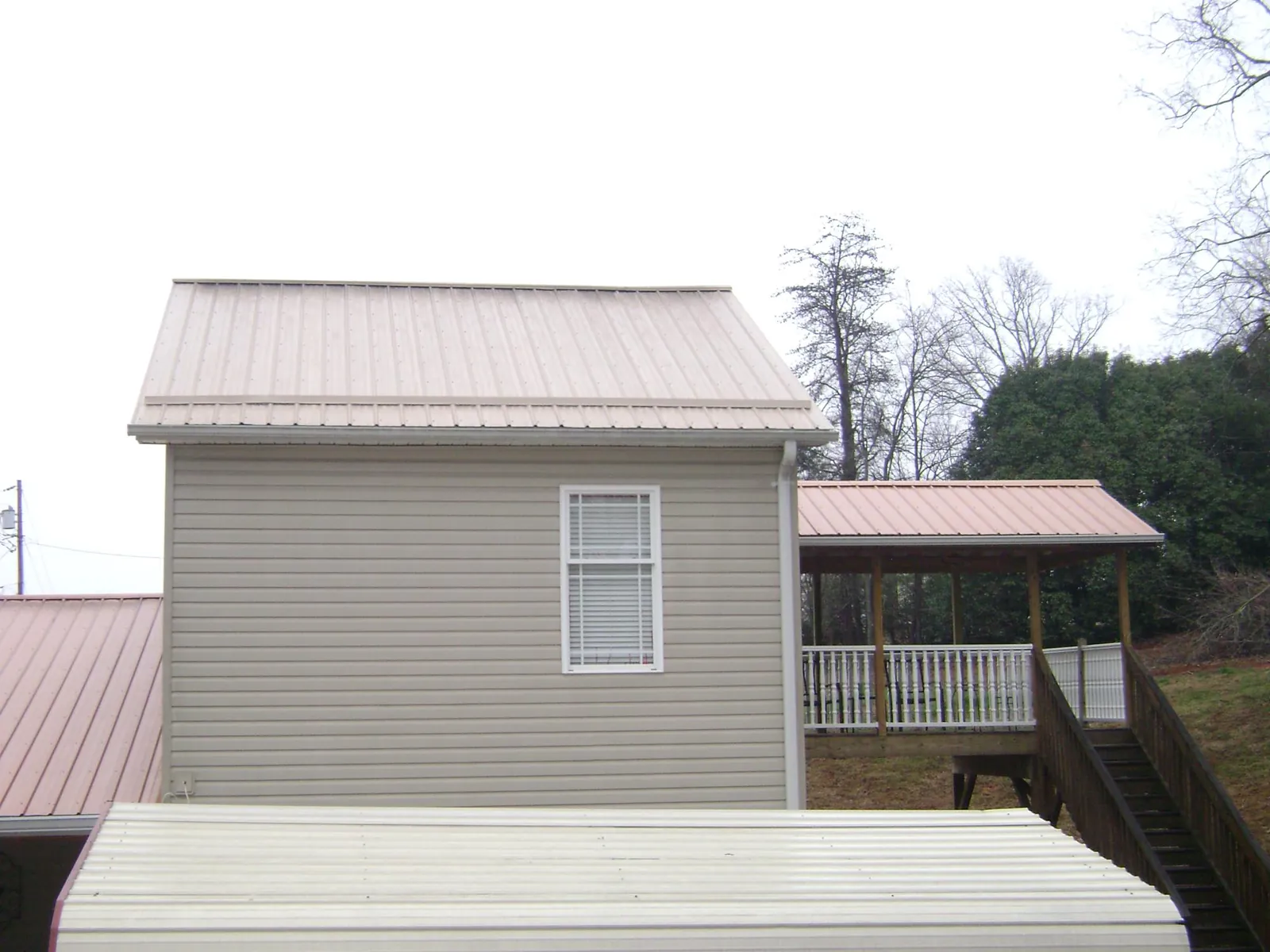 Tan metal roofs on a two story addition and attached porch, from a Roof Replacement job in Guymon