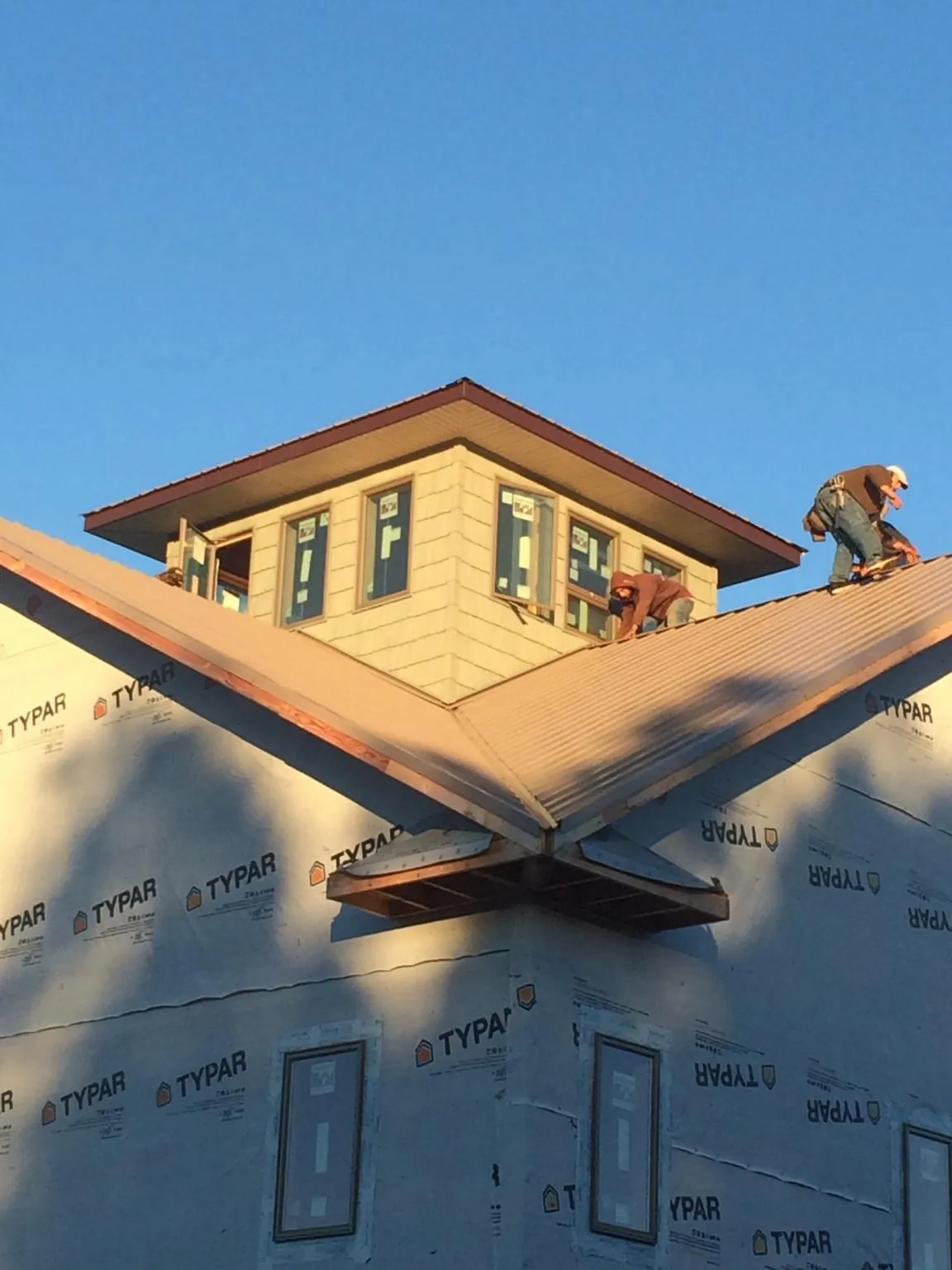 Roofers working around a rooftop cupola on a new metal roof at sunset — Roof Waterproofing in Guymon by Roofing Brothers